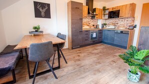 A modern kitchen with wooden cabinets, a brick backsplash, and a dining area with a wooden table and chairs. - Post Residence Apartments 11A Sauna Near Skilift (Zell am See)