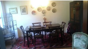 A dining area with a table and chairs, a patterned rug, wall decorations, and a birdcage. - House in the center of town, close to the sea (Cabourg)