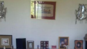 A bedroom with a floral bedspread, a shelf with framed pictures, and wall-mounted lamps. - House in the center of town, close to the sea (Cabourg)