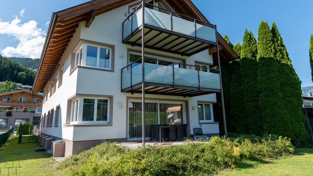 A two-story house with a balcony, a garden, and a mountainous backdrop. - Fourteen 2 1 Zell am See S P (Zell am See)