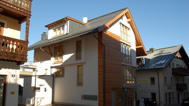A two-story building with a wooden facade and large windows, located in a street with other buildings. - Apartment Zell City - Next to ski Lift and Town (Zell am See)