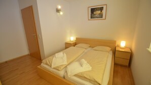 A neatly made double bed with two pillows, a wooden headboard, and two bedside tables with lamps. - Apartment Zell City - Next to ski Lift and Town (Zell am See)