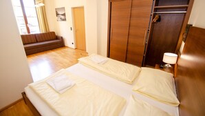 Een hotelkamer met twee bedden, een houten garderobe, een bank en een raam met gordijnen.