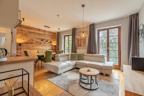 A modern living room with a sectional sofa, a dining area, and large windows.