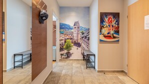 Un couloir orné d’une fresque représentant une place de ville, avec une porte en bois et un tableau représentant un vélo.