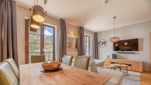 Un salon moderne avec une table à manger en bois, des canapés et un téléviseur fixé au mur.