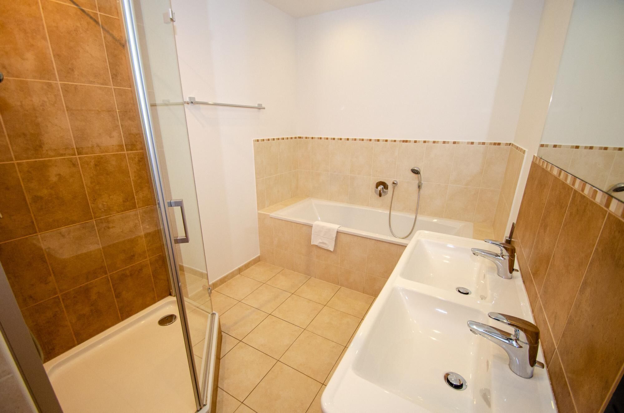 A bathroom with a glass shower enclosure, a bathtub, and two sinks.
