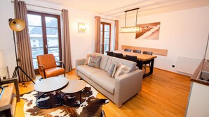 A modern living room with a sofa, two round tables, a dining table, and a cowhide rug. - Post Residence Apartments 7B 150m From ski Lift (Zell am See)