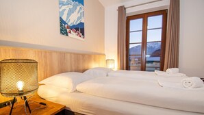 A hotel room with a bed, a nightstand with a lamp, a window with curtains, and a poster on the wall. - Post Residence Apartments 7B 150m From ski Lift (Zell am See)