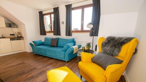 A living room with a blue sofa, a yellow armchair, and a small table with a lamp. - Post Residence Apartments 10B Sauna Near ski lif (Zell am See)