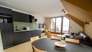 Eine moderne Küche mit dunklen Schränken, einer grünen Spritzschutzwand und einem Essbereich mit rundem Tisch und Stühlen.