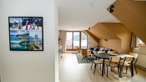Ein moderner Essbereich mit einem runden Tisch und Stühlen, einer Couch und einem großen Fenster mit Blick auf einen Berg und einen See.