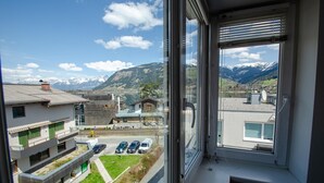 Uitzicht vanuit een raam op een parkeerplaats, gebouwen en bergen.