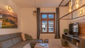 A modern living room with a sofa, a coffee table, a TV, and a painting on the wall. - Post Residence Apartments 1C Sauna Near ski Lift (Zell am See)