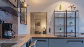 A modern kitchen with a coffee maker, a built-in dishwasher, and a glass-fronted shelving unit with plants. - Post Residence Apartments 3C 150m From ski Lift (Zell am See)