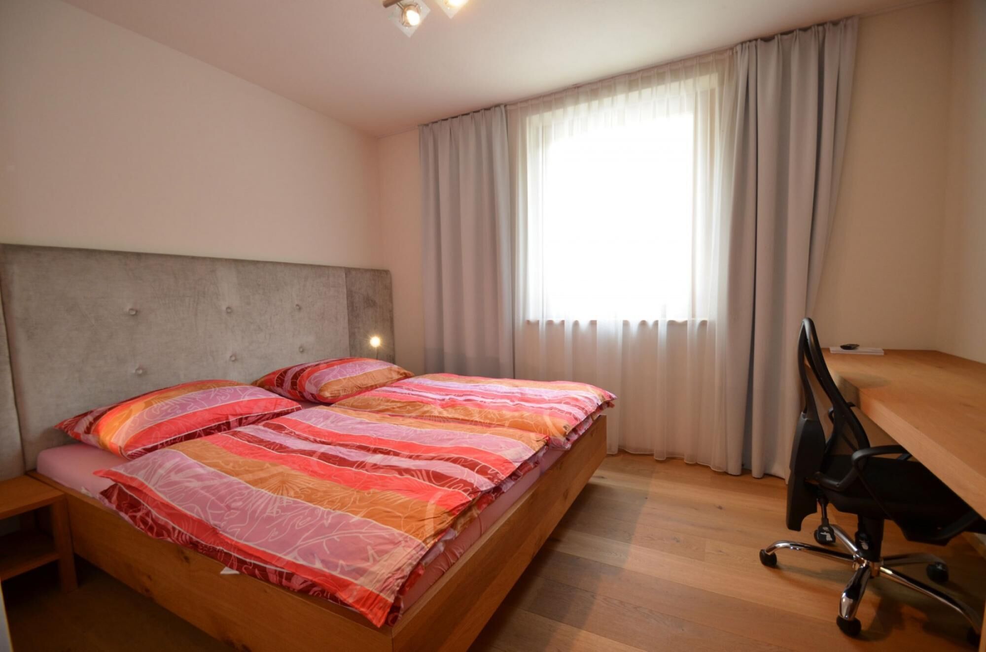 Ein Schlafzimmer mit Bett, Schreibtisch und Stuhl.