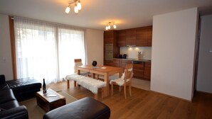 Una sala de estar moderna con una mesa de comedor de madera, un sofá de cuero y una cocina con armarios de madera y electrodomésticos.