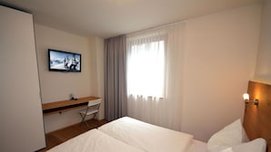 Una habitación de hotel con cama, escritorio y televisión.