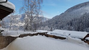 Paisaje nevado de una montaña con una valla de madera y un edificio con techo inclinado.