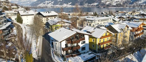 A snow-covered town with buildings along a river, surrounded by mountains.