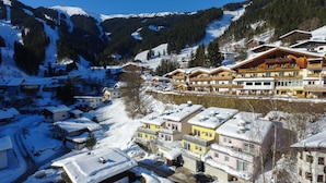 A snow-covered mountain village with traditional wooden buildings and a ski resort in the background. - Apartment Summer Winter Fun II - 200 m From ski (Zell am See)