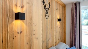 A room with a wooden wall, two black wall-mounted lights, and a large window with curtains. - Apartment Summer Winter Fun II - 200 m From ski (Zell am See)