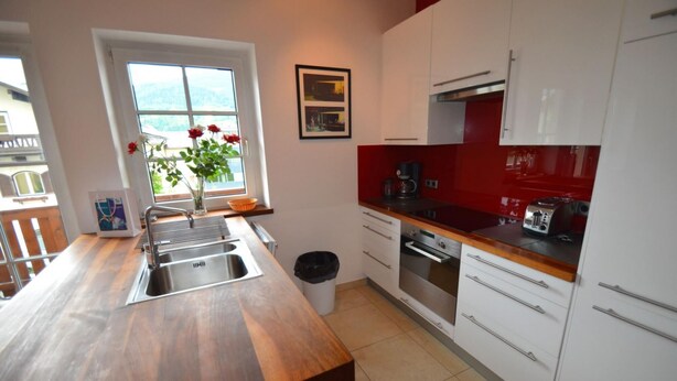 Una cocina moderna con encimera de madera, pileta de acero inoxidable y armarios blancos.