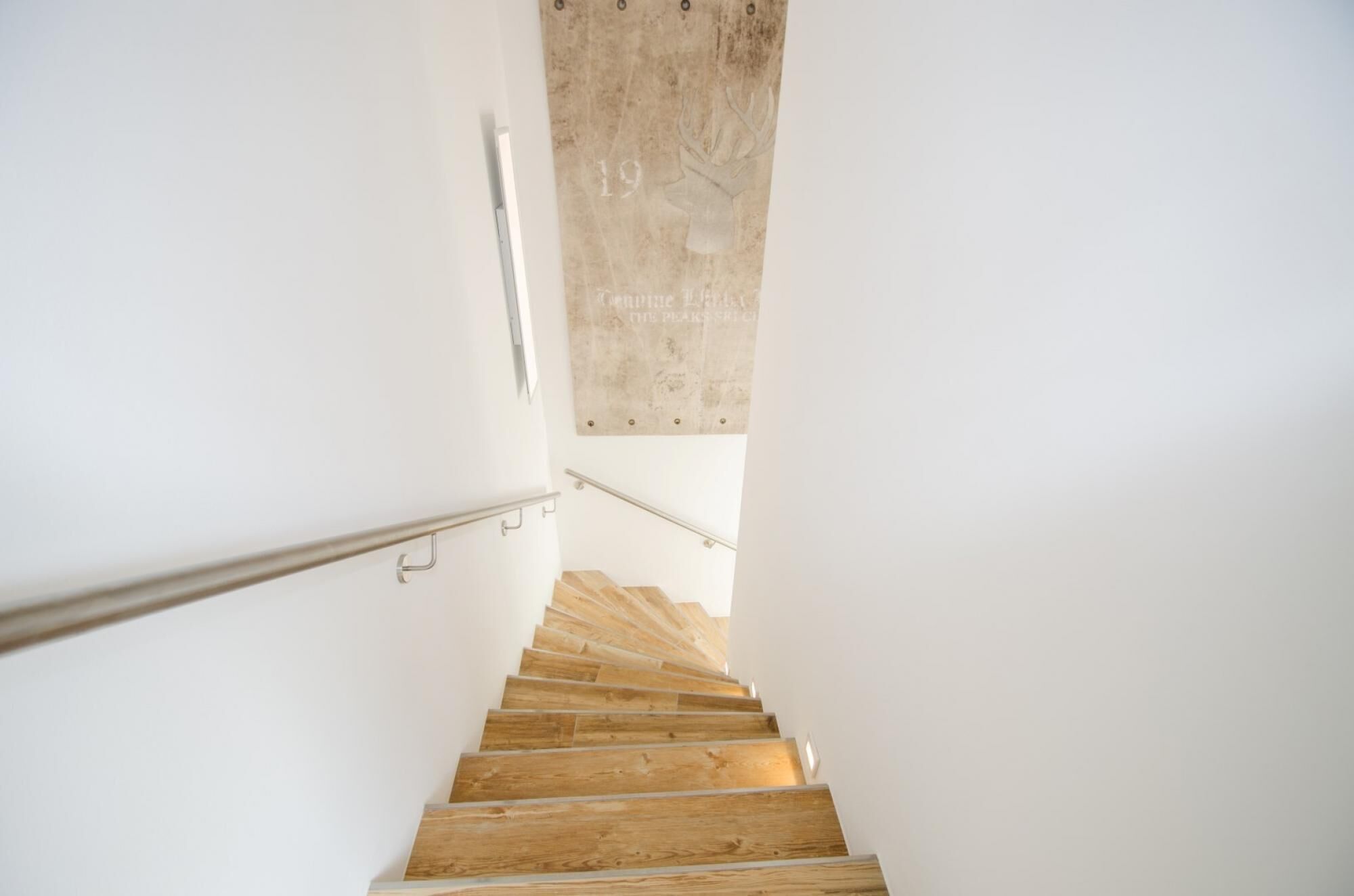A wooden staircase with metal handrails, leading upwards in a modern interior.