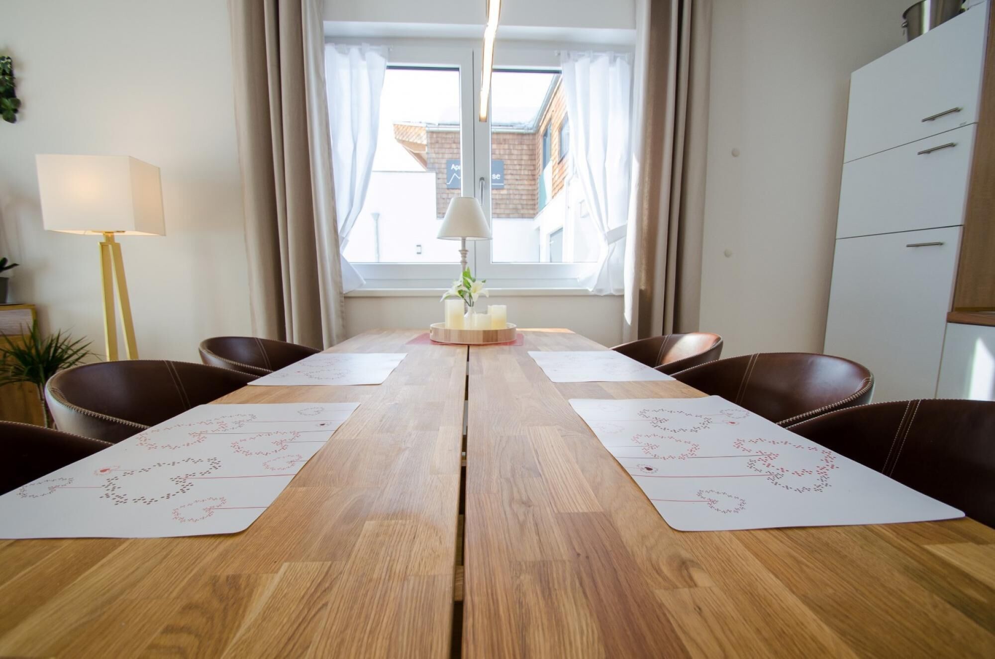 Un coin repas avec une table en bois, quatre chaises et une fenêtre avec des rideaux.