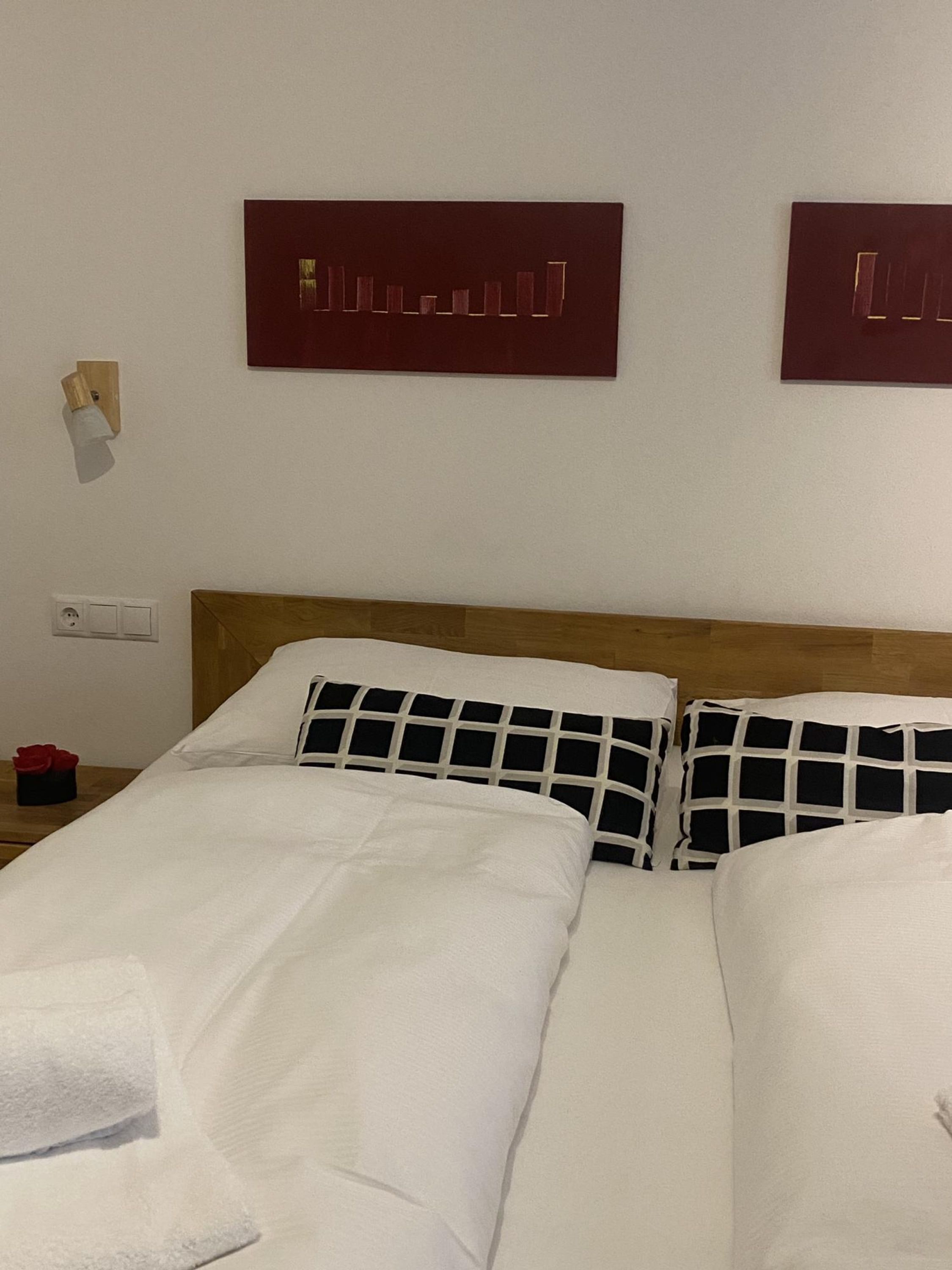 A hotel room with two beds, white bedding, a wooden headboard, and two wall-mounted artworks.