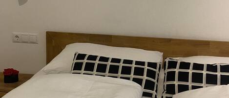 A hotel room with two beds, white bedding, a wooden headboard, and two wall-mounted artworks.