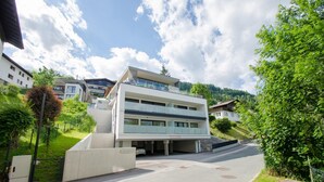 A modern multi-story building with a flat roof, large windows, and a covered parking area. - Superb Alpine Lodges Zell am See 6-8pax (Zell am See)