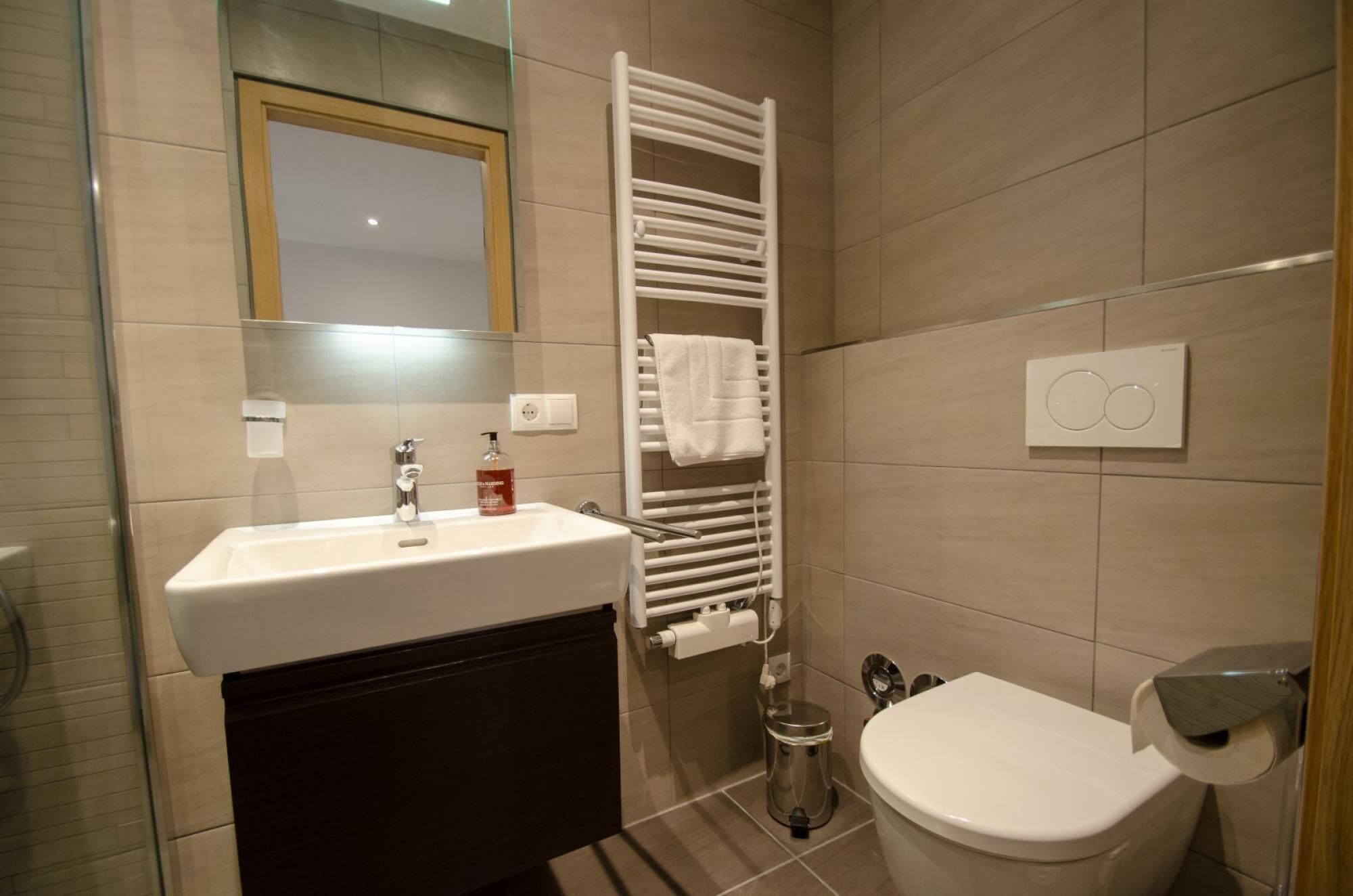Een moderne badkamer met een wastafel, toilet, handdoekhouder en een spiegel.