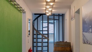 Un escalier avec une rampe en bois, un extincteur et un baril posé sur le sol.
