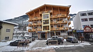 Ein mehrstöckiges Hotel mit hölzernen Balkonen und einer Seilbahn im Hintergrund.