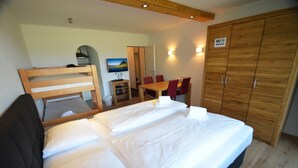 A bedroom with a bed, a wooden wardrobe, a desk with chairs, and a television. - Deluxe Studio Kaprun TOP 12 (Kaprun)