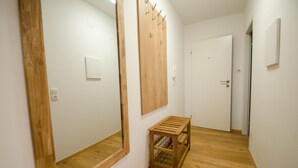 A hallway with wooden flooring, a wooden bench, a large mirror, and a wooden coat rack. - Deluxe Studio Kaprun TOP 23 (Kaprun)
