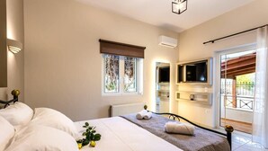 Un dormitorio con cama, ventana con persianas, televisor montado en la pared y un radiador.