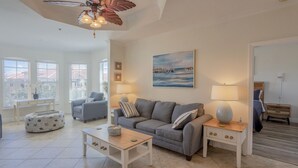A living room with a grey sofa, two side tables with lamps, a coffee table, and a painting of a seascape.