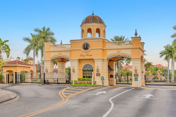 A hotel entrance with a clock, palm trees, and a clear sky.