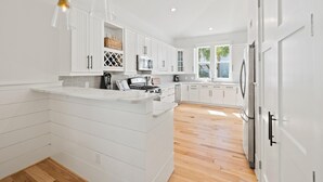 A modern kitchen with white cabinetry, a central island, and a large window.