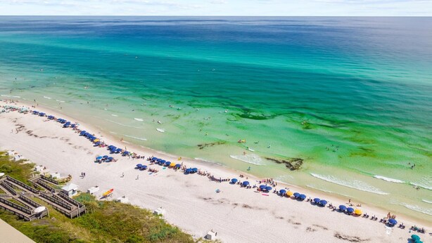 A beach with clear turquoise water and a long row of umbrellas along the shore.