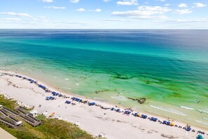 A beach with clear turquoise water and a long row of umbrellas along the shore. - Seacrest Home with Pool and Wet Bar (Seacrest Beach)