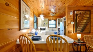 Un interior de madera con comedor, cocina y escalera.