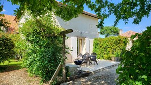 A house with a gravel driveway, a wooden pergola, and a barbecue grill.