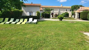 A villa with a tiled roof, a well-maintained lawn, and several lounge chairs.