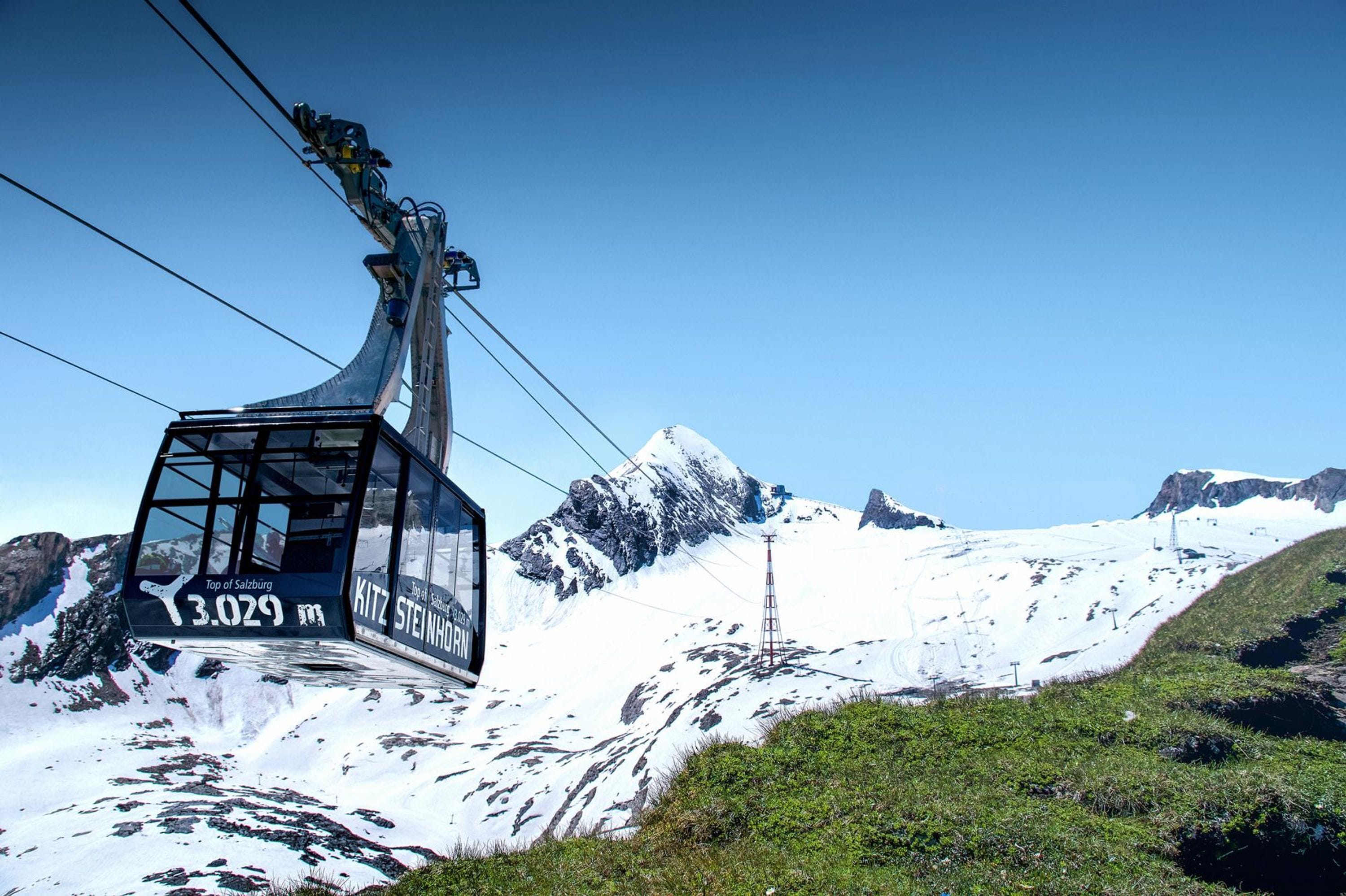 A cable car at the top of a mountain with a clear sky and snow-covered landscape.