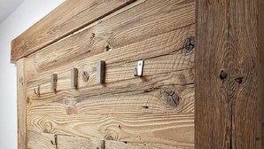 A wooden wardrobe with multiple hooks and a phone. - Penthouse Eightyone Kaprun Incl Summer Card (Kaprun)