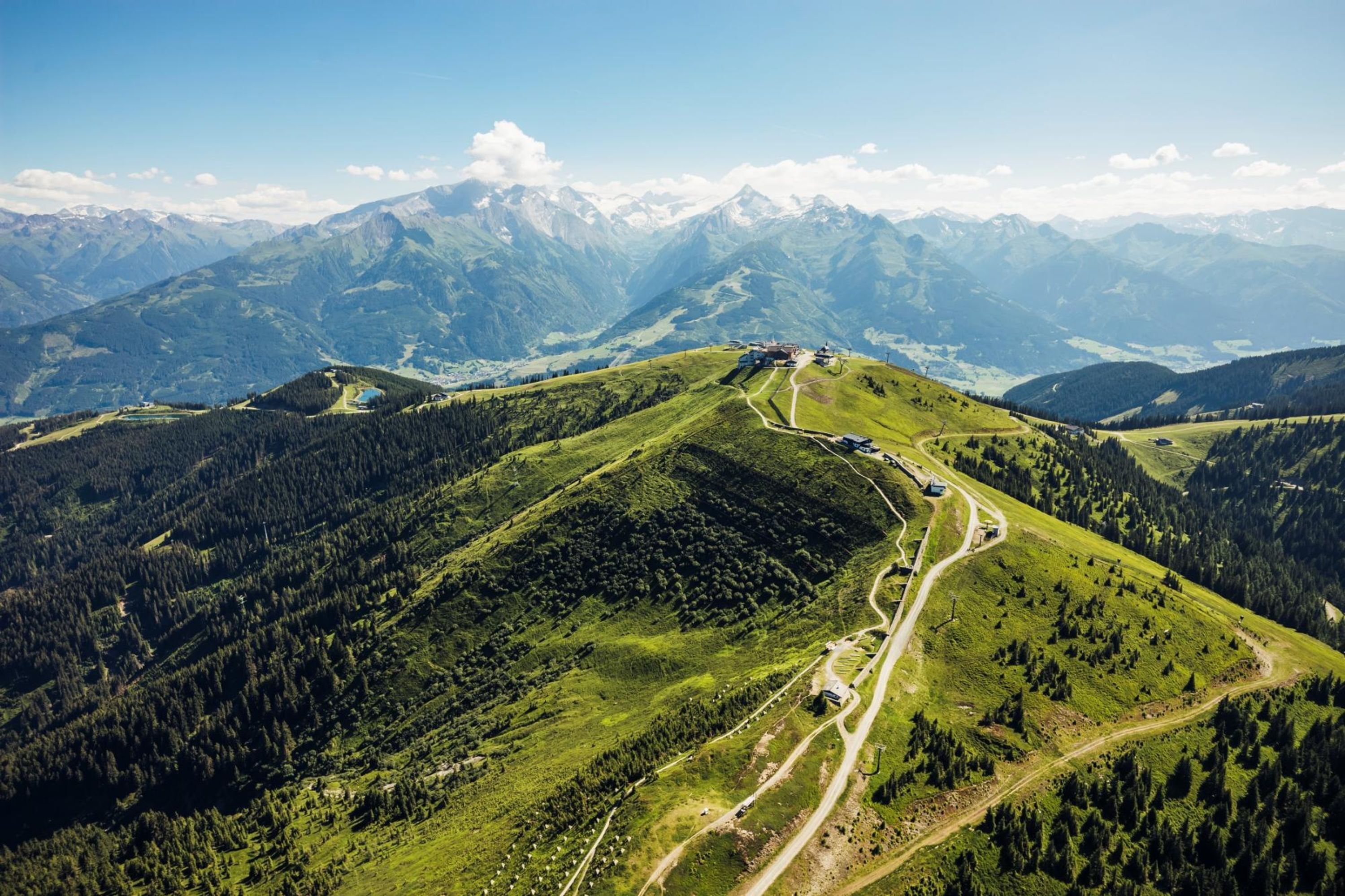 A mountainous landscape with a winding road and a building on a hill.