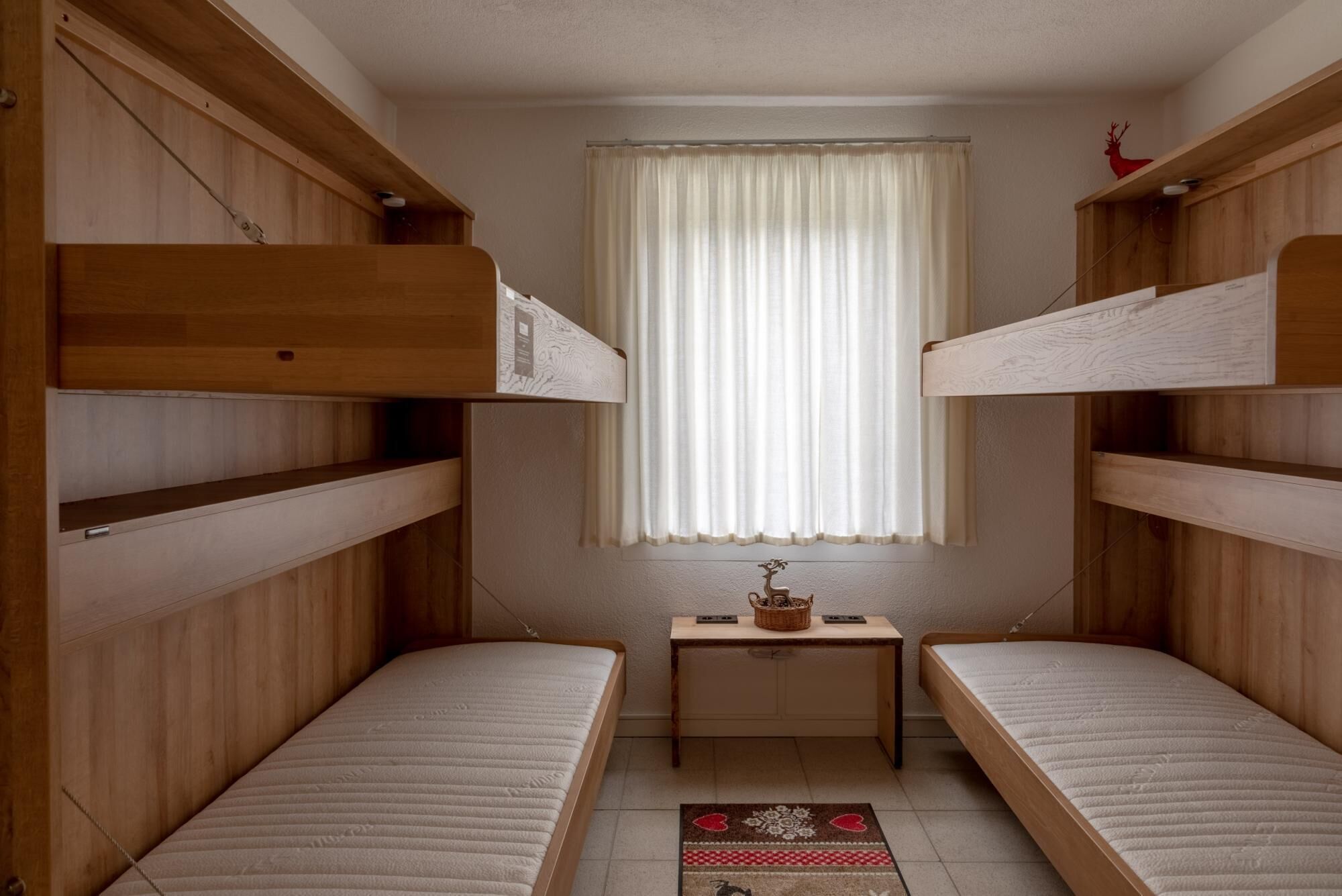 Een kleine kamer met twee stapelbedden en een bureau met een mandje.